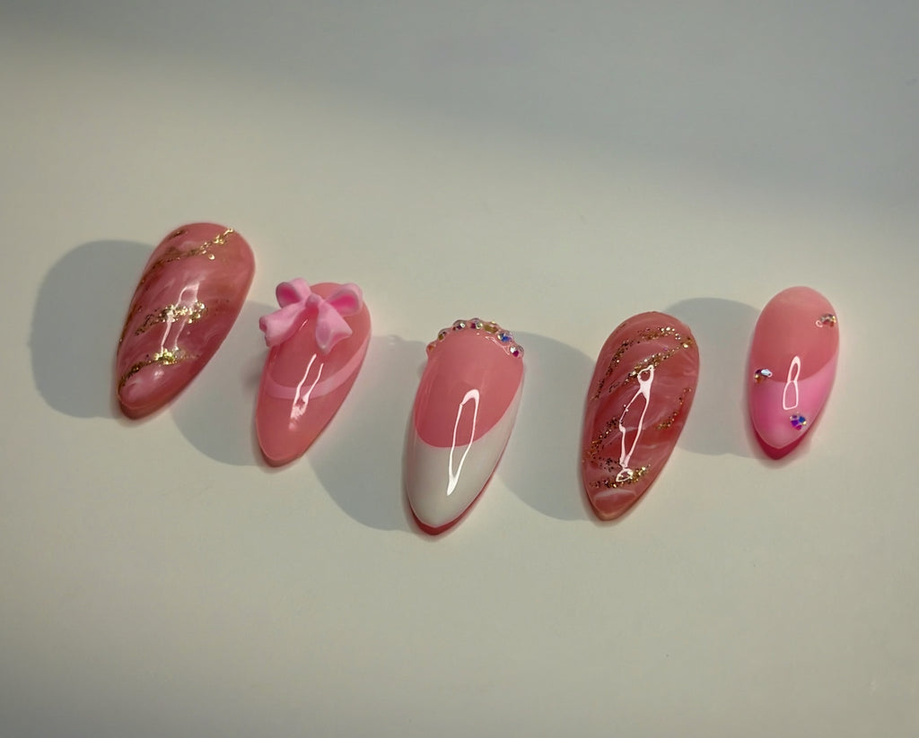 Set of pink and gold decorative nails on a white background